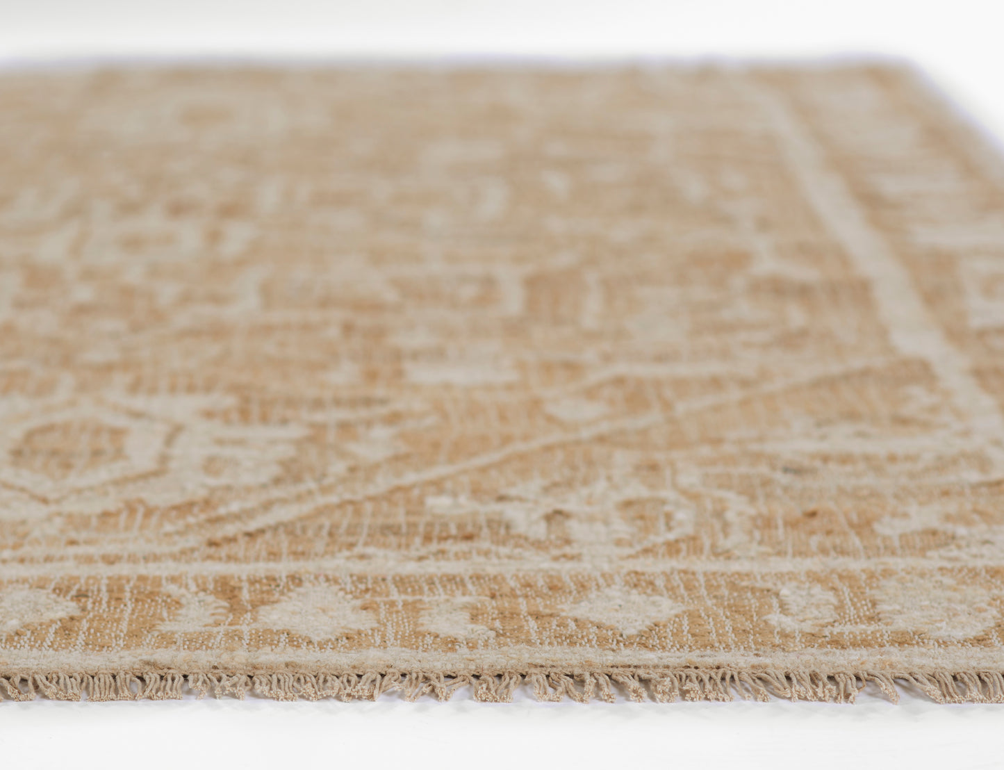 Beige woven area rug with ivory floral pattern and fringed edges.