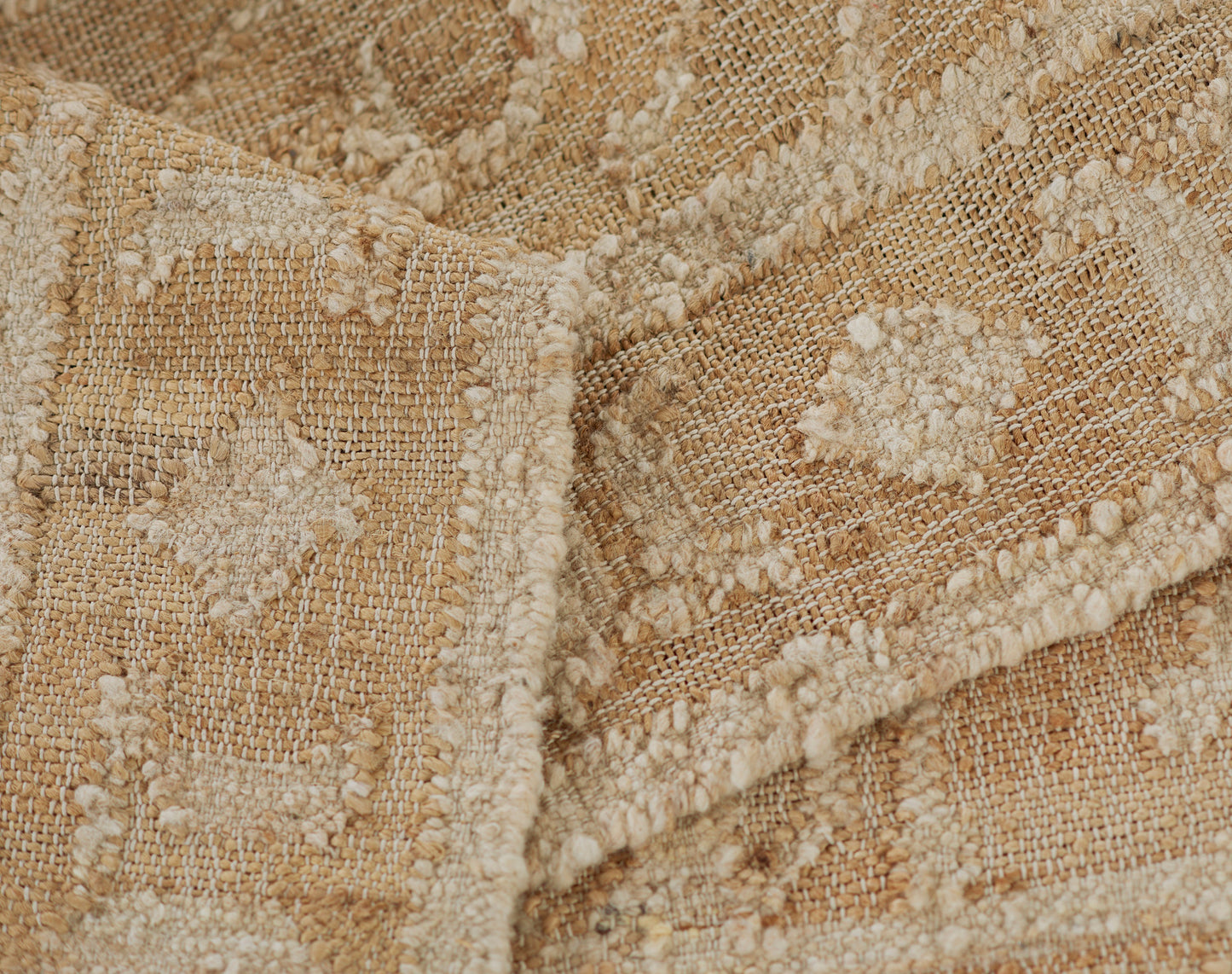 Beige and cream woven rug with textured geometric motifs and a soft, nubby surface.