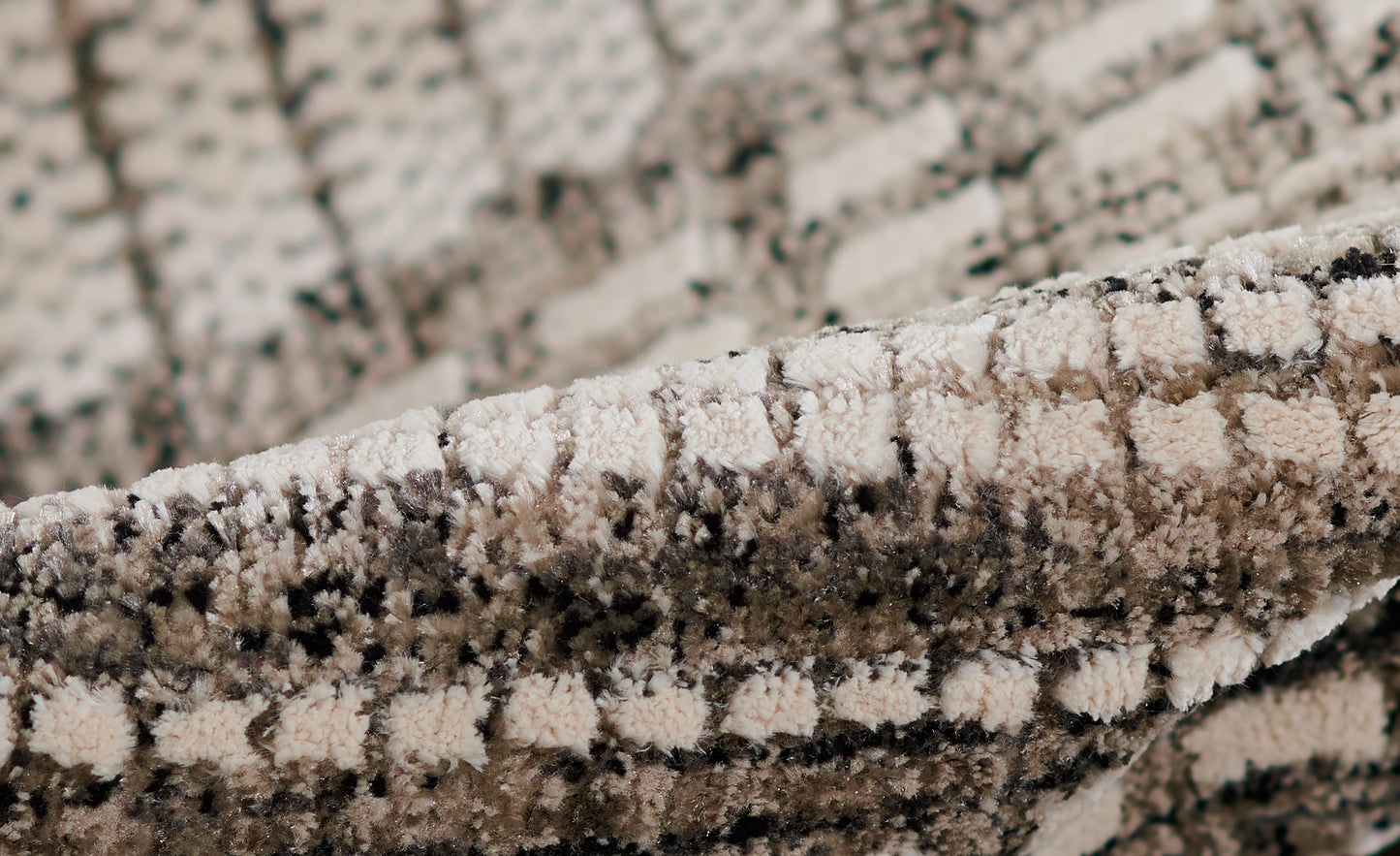 Close-up of a beige & gray shag rug with a plush, looped pile & speckled geometric pattern.