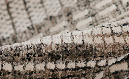 Close-up of a beige & gray shag rug with a plush, looped pile & speckled geometric pattern.