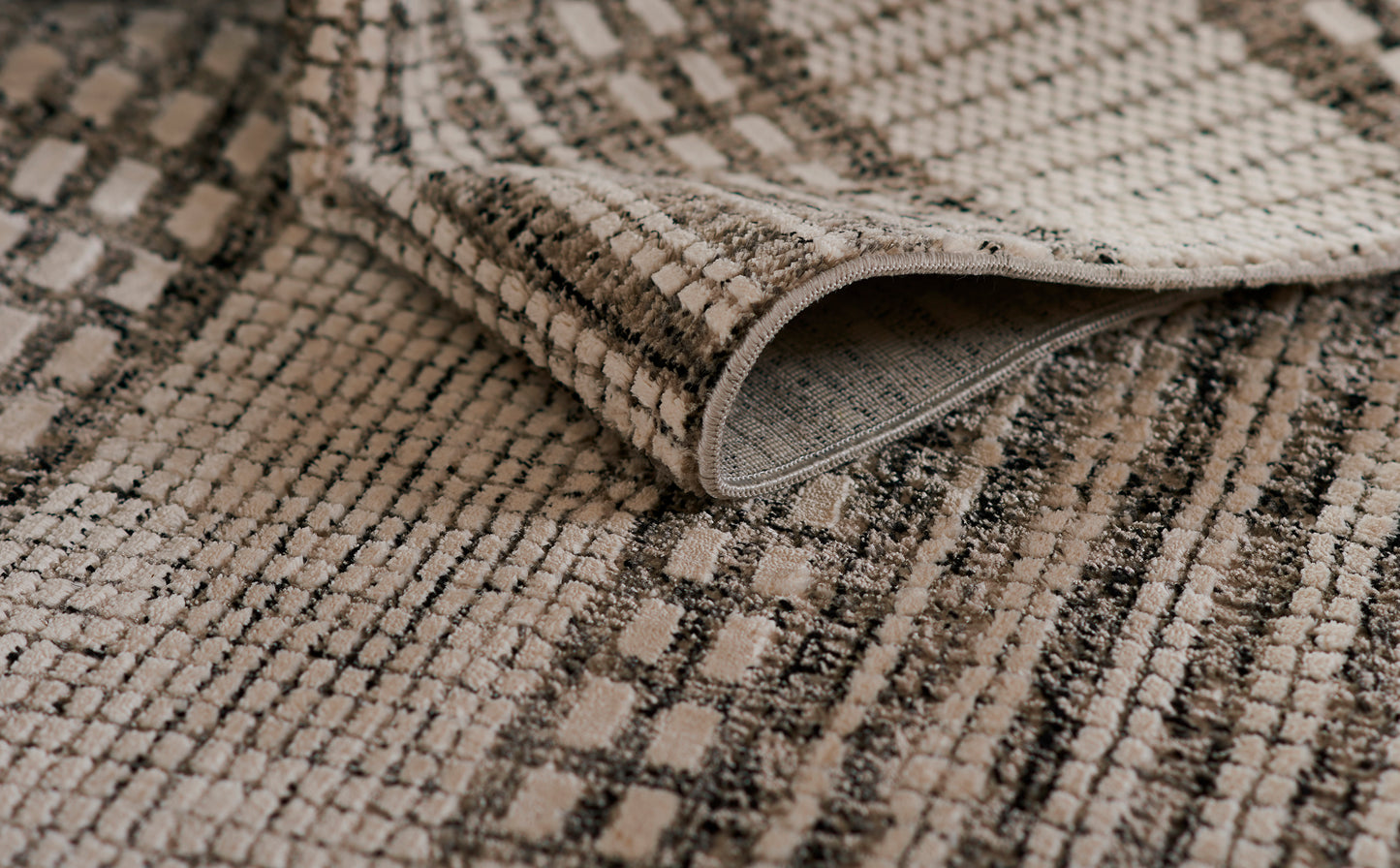 Beige and taupe patterned woven rug with plush loop pile and rolled edge, casual living-room style.