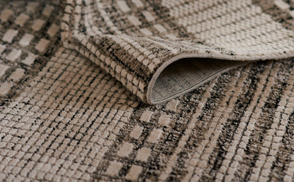 Beige and taupe patterned woven rug with plush loop pile and rolled edge, casual living-room style.