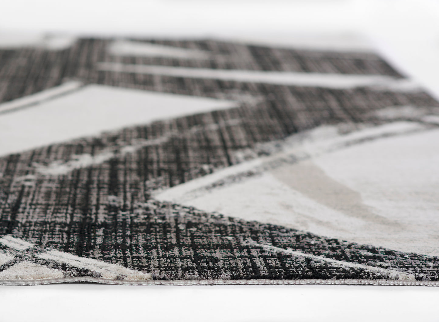 Rectangular modern area rug with black, white and gray geometric triangles; low-pile, woven texture.