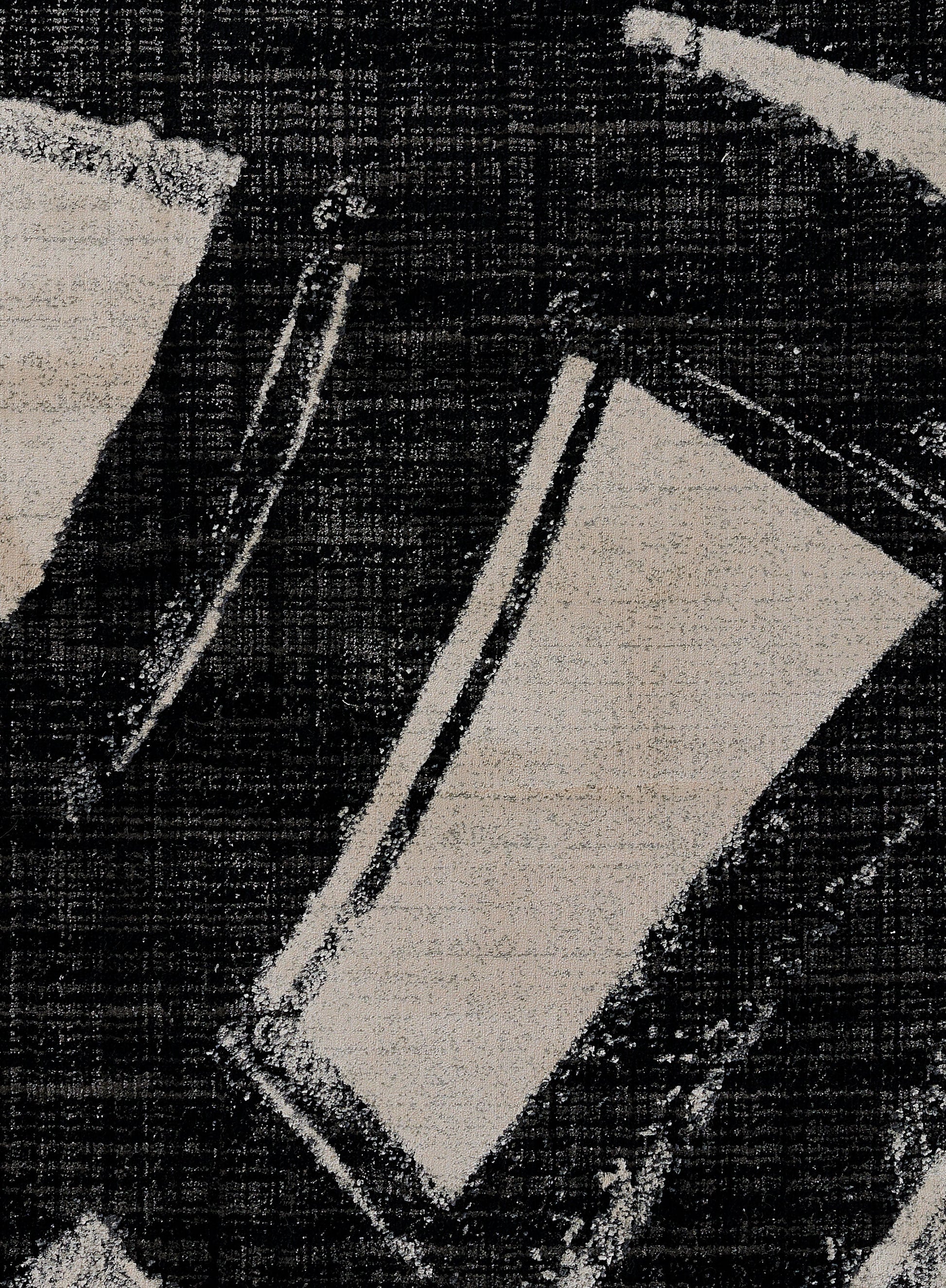 Close-up of a modern abstract rug featuring ivory geometric shapes on a black woven background.