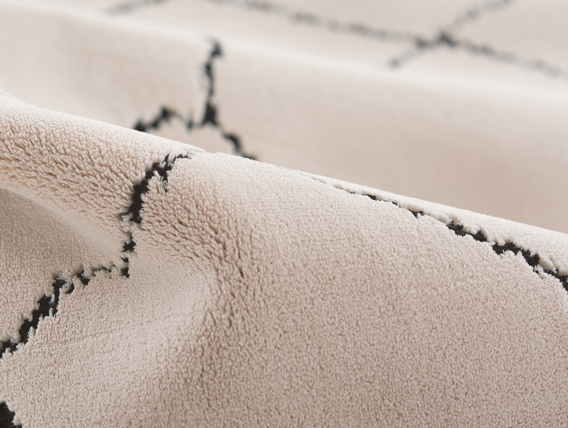 Ivory plush suede-like fabric with black zigzag stitching; cozy 2' x 3' rug.