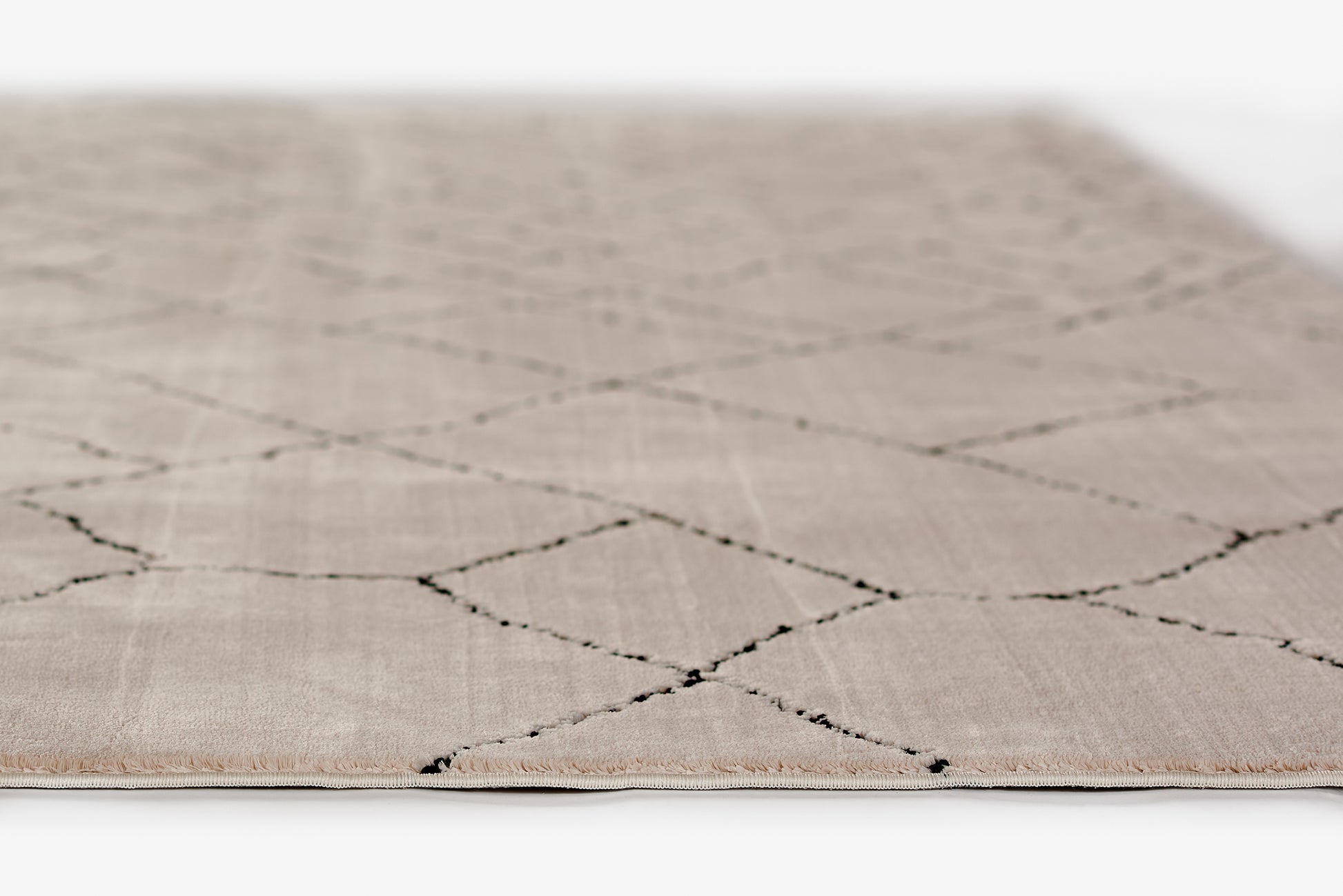 Beige ivory rug with black diamond lattice, flat-weave texture and short fringe along edges.