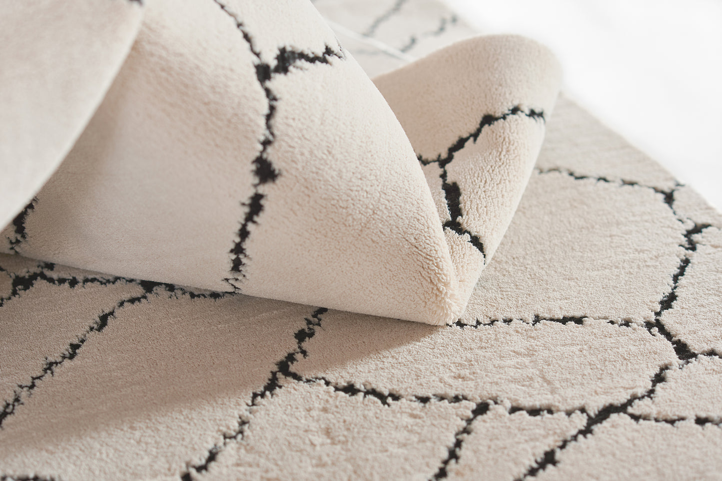 Beige tufted rug with an irregular black crack-like grid and plush soft pile for modern living spaces.