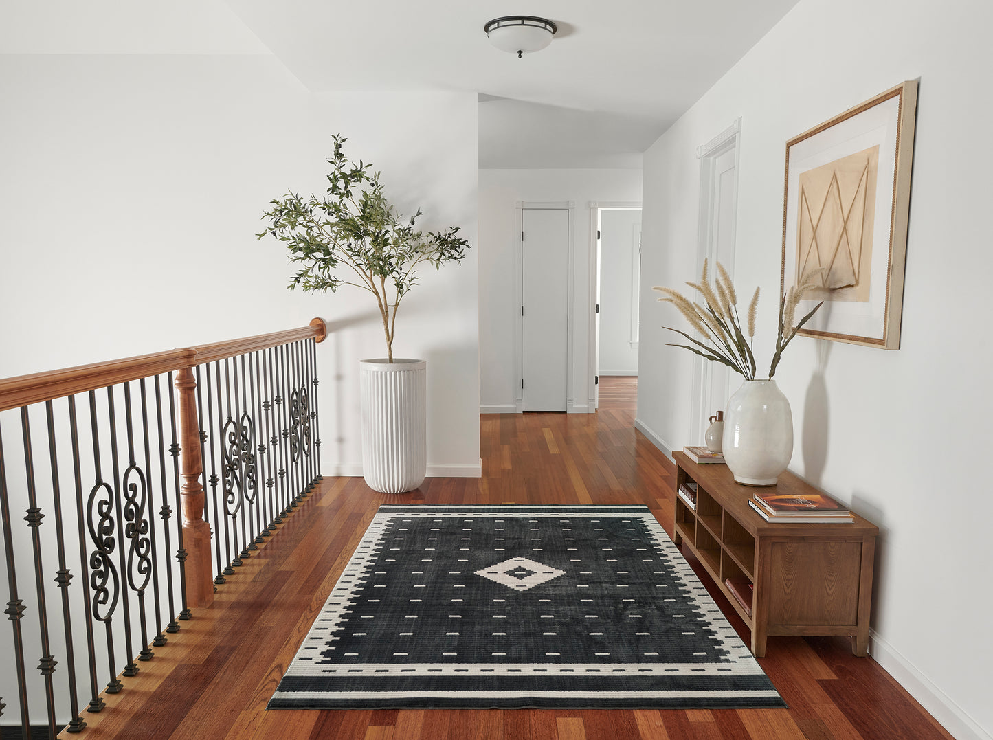 NoHo black geometric area rug with a white diamond center and bordered edges in a hallway with hardwood floors and modern decor.