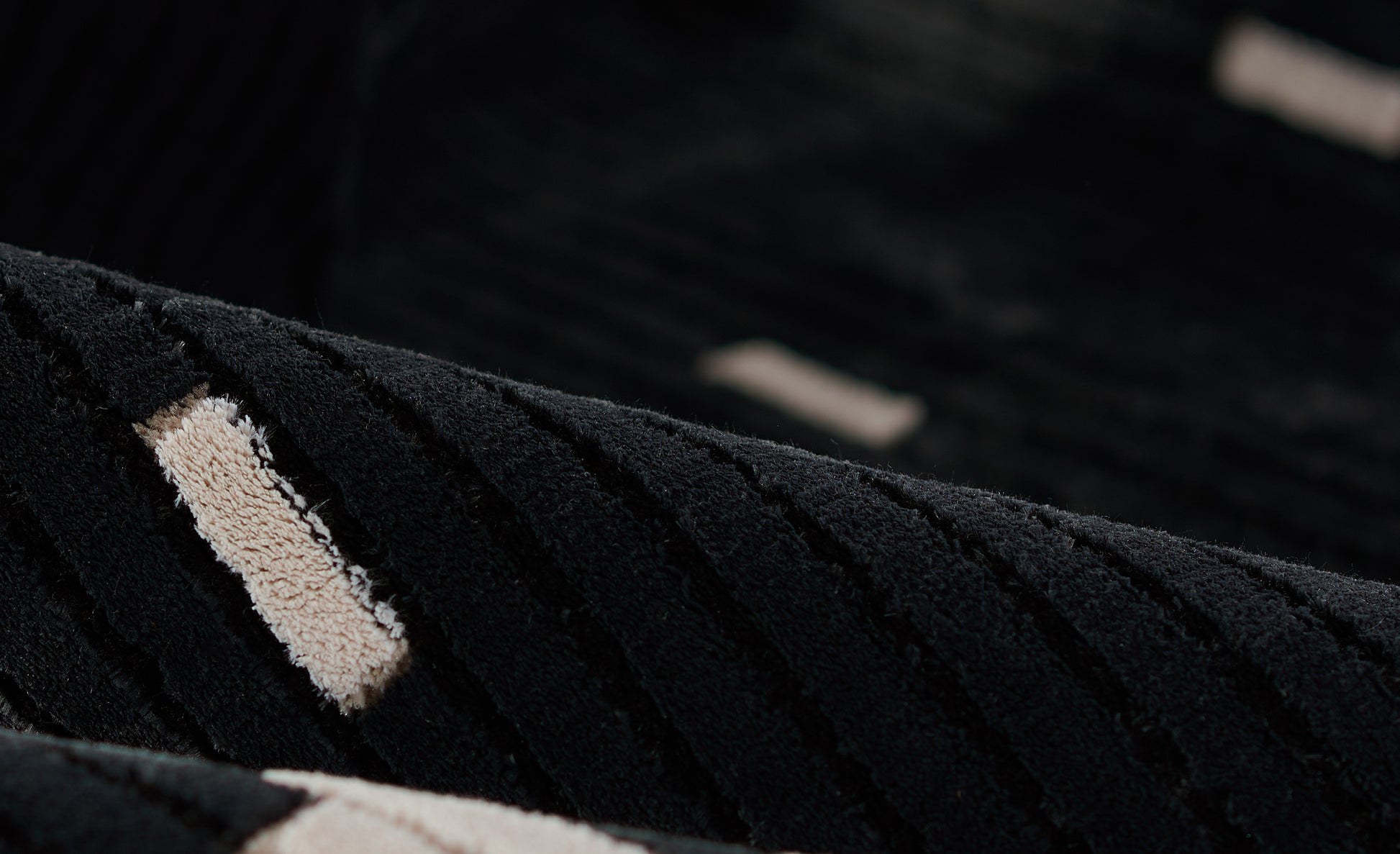 Close-up of black waffle-knit rug with a beige rectangular patch accent, soft plush texture.