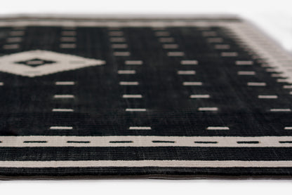 Black woven rug with white geometric border and diamond motif; modern flat-weave.