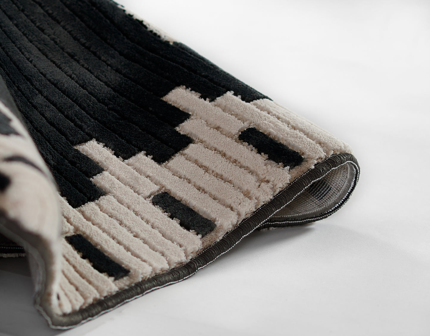 NoHo black beige geometric rug with plush ribbed pile and bound edge; modern home decor mat.
