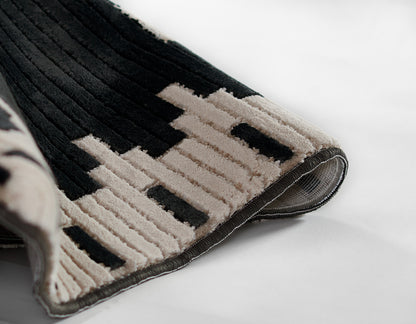 NoHo black beige geometric rug with plush ribbed pile and bound edge; modern home decor mat.