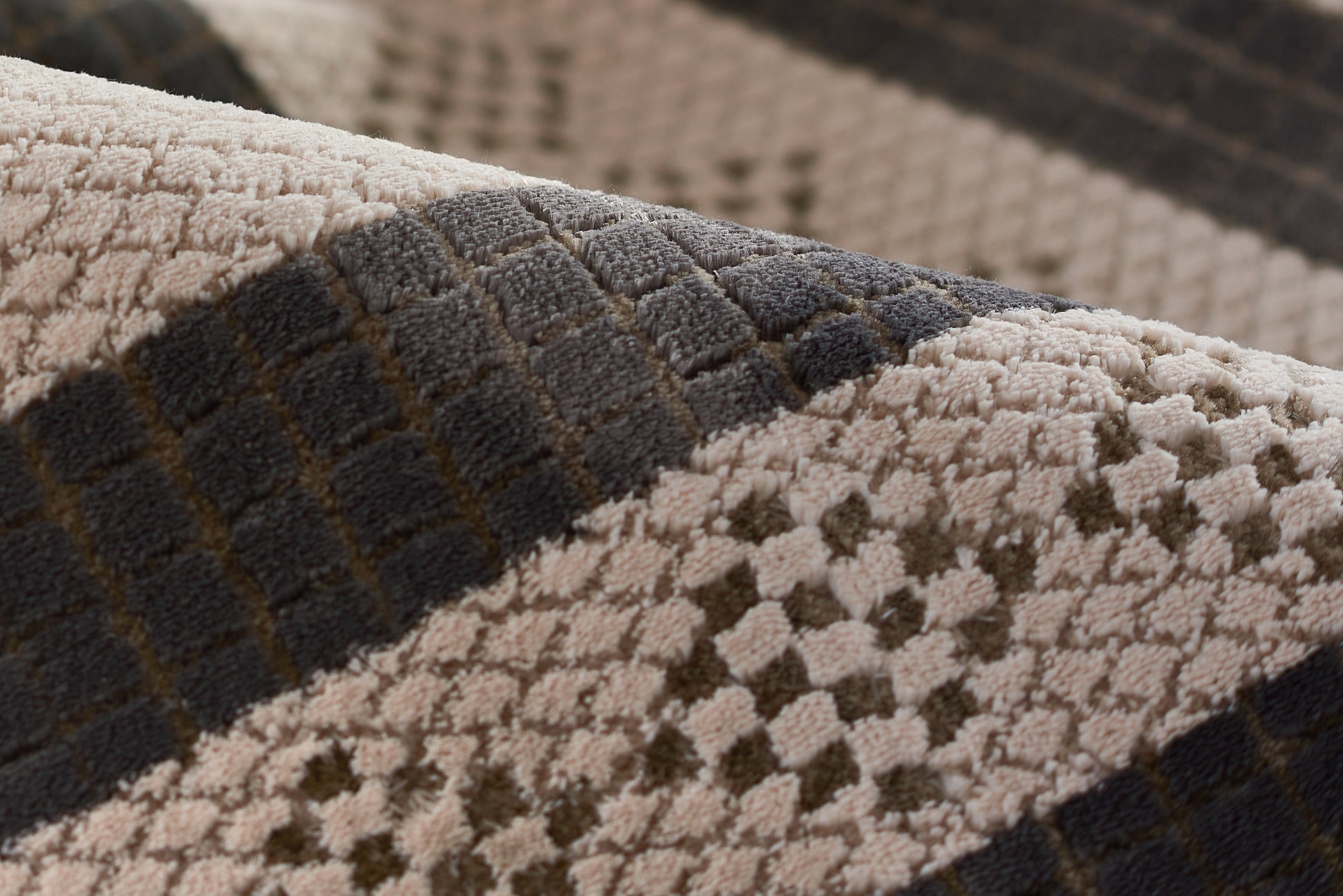 Close-up of plush beige and ivory rug with dark gray checkered squares and chunky textured pile.