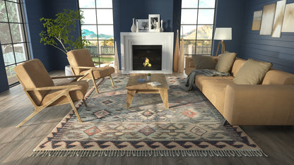 Nomad blue geometric area rug with fringe; ivory, slate blue and peach accents under a wooden coffee table in a living room.
