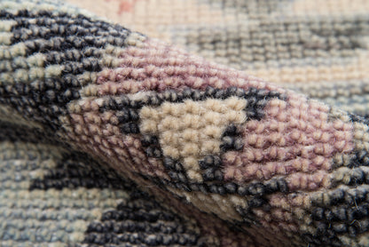 Close-up of soft looped-pile rug in beige, cream, navy and pink with geometric nomad motif.
