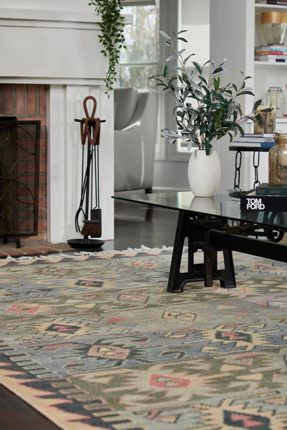 Geometric tribal area rug in muted greens, blues, pinks and beiges; woven kilim-inspired pattern for living room decor.