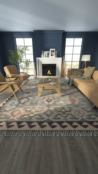 Geometric blue and neutral area rug with fringe, in a modern living room with tan sofa, wood coffee table, and navy walls.