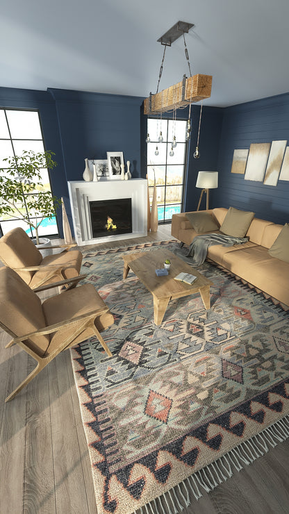 Blue geometric Nomad rug with fringe, blues and beige tones, in a living room with tan seating and a wooden coffee table.