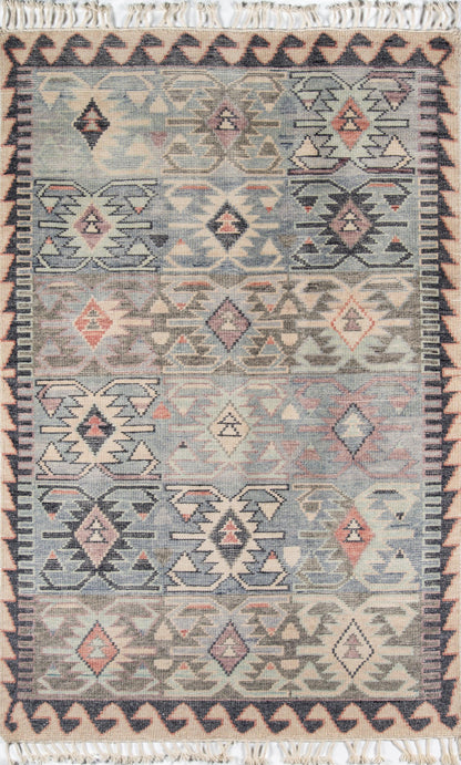 Nomad-style kilim rug with geometric diamond motifs in blue, beige, pink and navy; fringed ends.