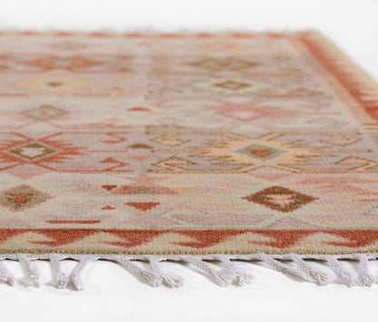 Geometric area rug in warm peach, pink, and beige tones with tassel fringe, 8' x 11'.