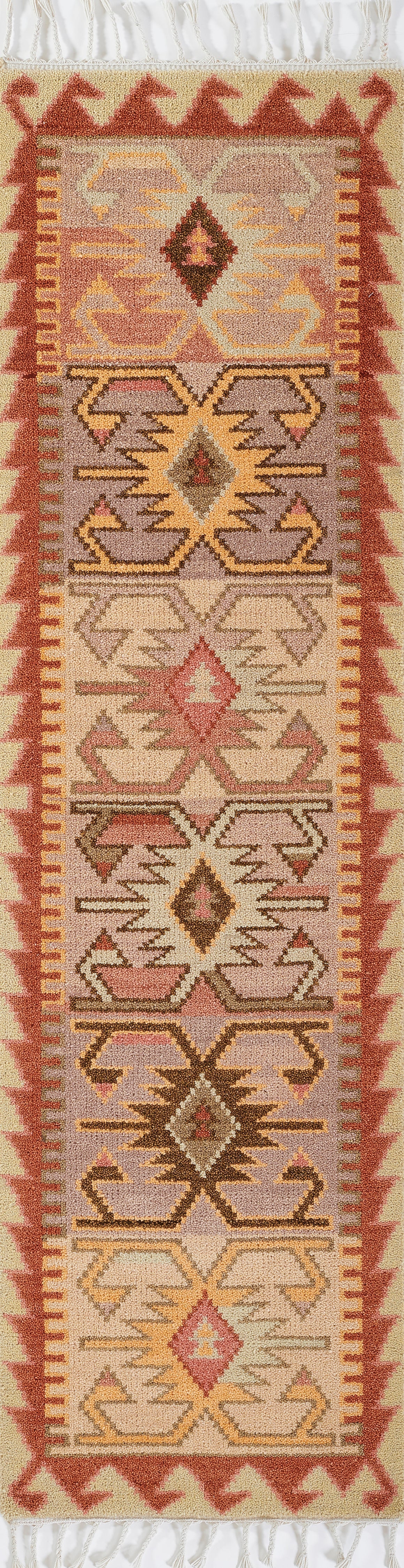 Nomad kilim runner rug with geometric diamond motifs in pink, lavender, beige and yellow; red border and white fringe.
