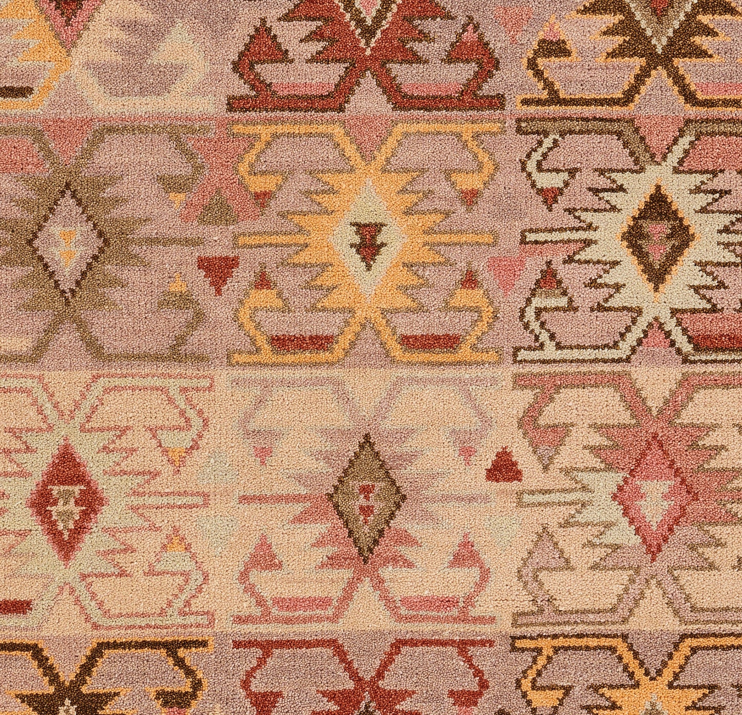 Nomad-style geometric rug with diamonds and zigzags in pink, peach, beige, brown and yellow.
