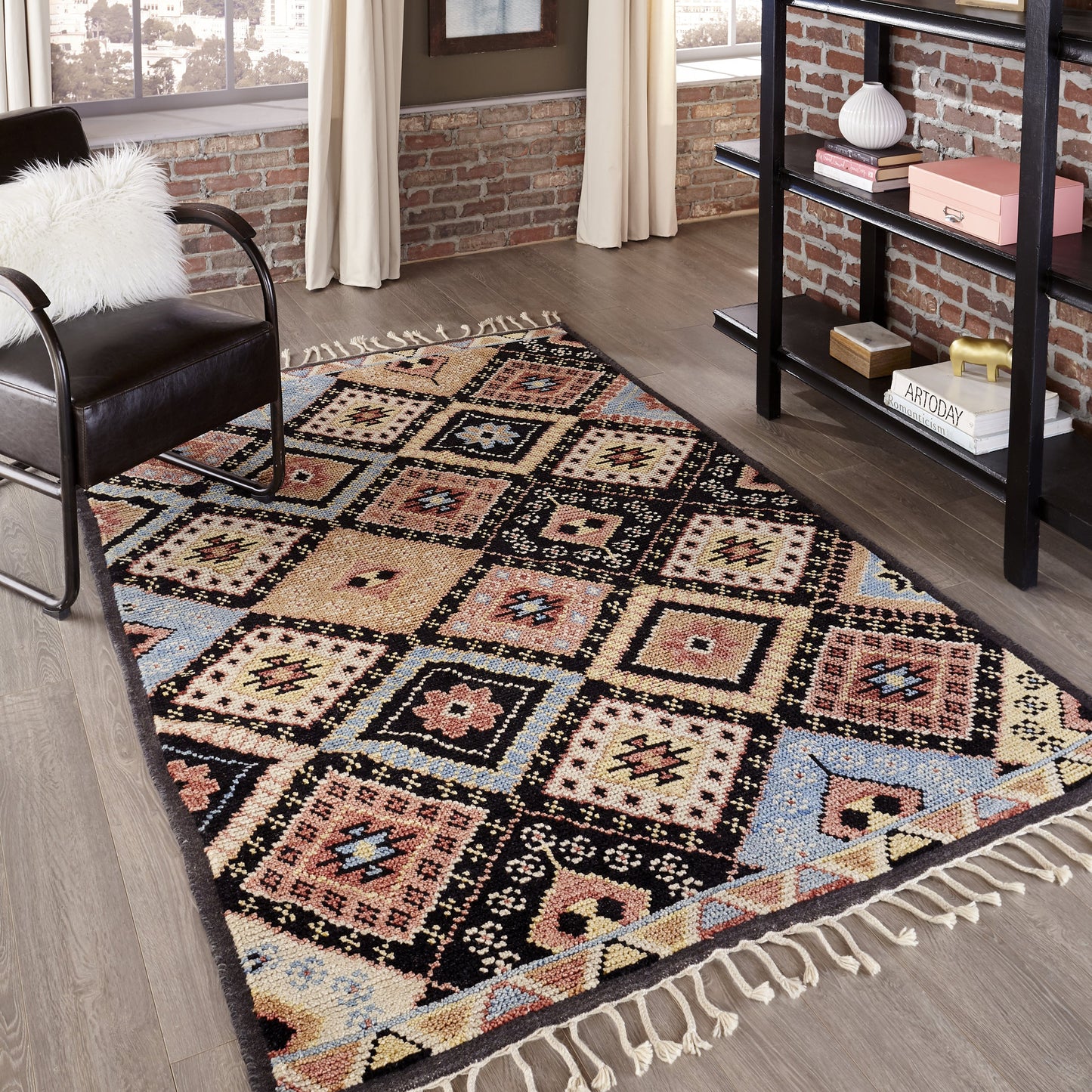 Kilim-style woven area rug with a multicolor diamond pattern in cream, pink, blue and yellow, bordered in dark tones, fringed ends.