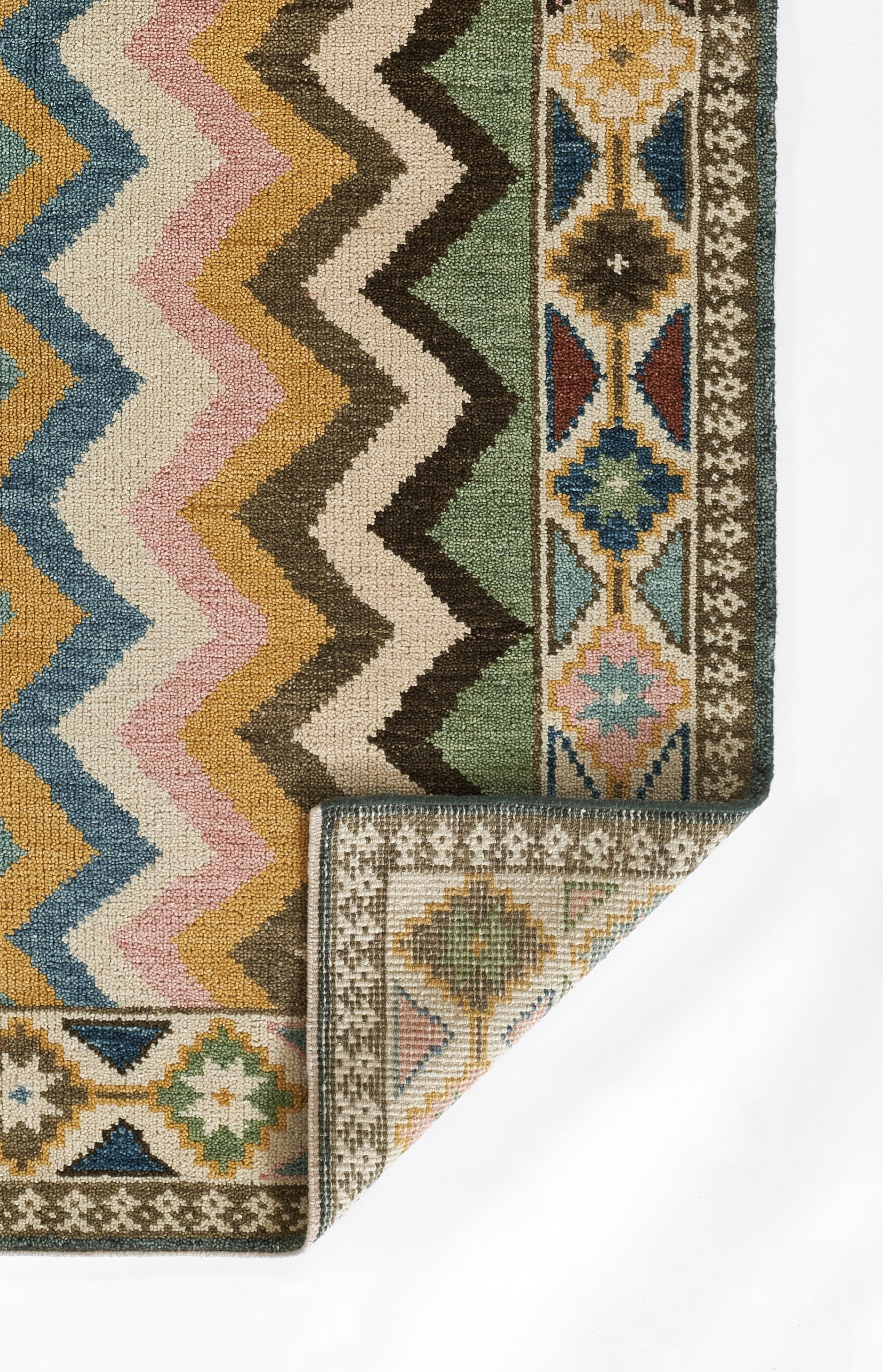 Colorful kilim-style rug with multicolor chevron zigzags and geometric border; nomad-inspired design.