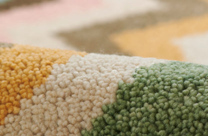 Close-up of a chunky loop rug in mustard yellow, cream and sage green; soft, textured home decor.