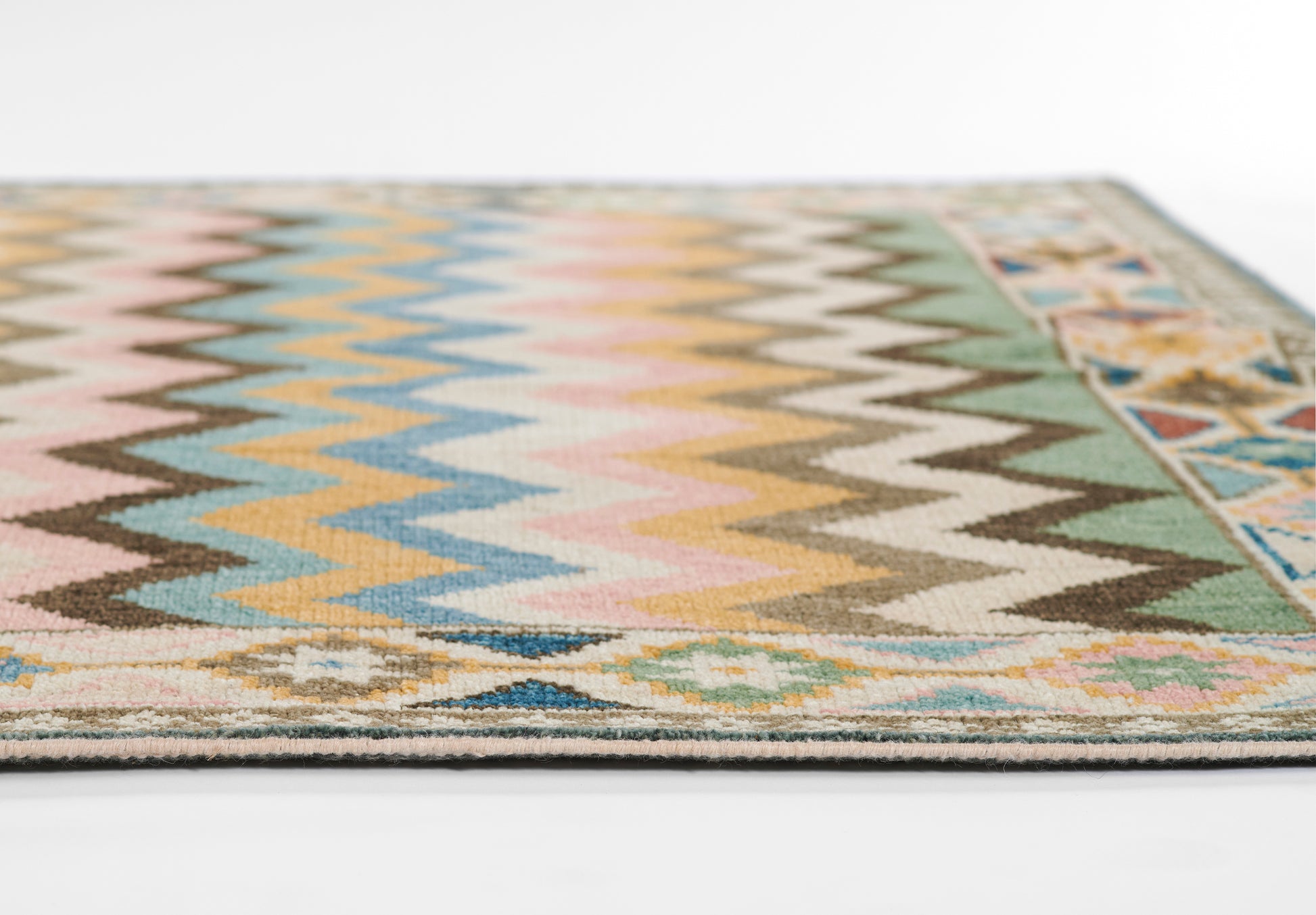 Boho nomad rug with pastel zigzag chevrons and a geometric border in pink, blue, yellow and green.
