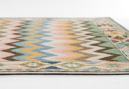 Boho nomad rug with pastel zigzag chevrons and a geometric border in pink, blue, yellow and green.