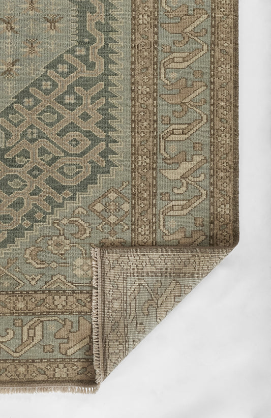 Muted teal and taupe geometric oriental rug with ornate border and woven texture, fringe edge.