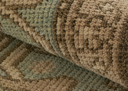 Close-up of a textured boucle rug with earthy tan, brown and sage green loops; thick pile, geometric pattern.