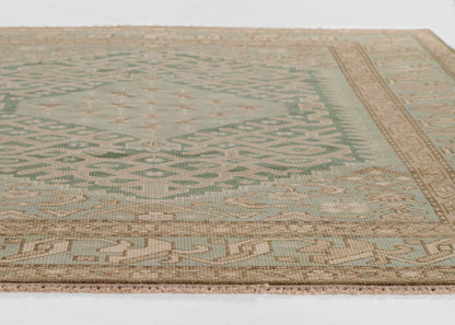Flatweave rug in sage green with tan border; geometric tribal diamonds, fringed edges for a nomadic look.