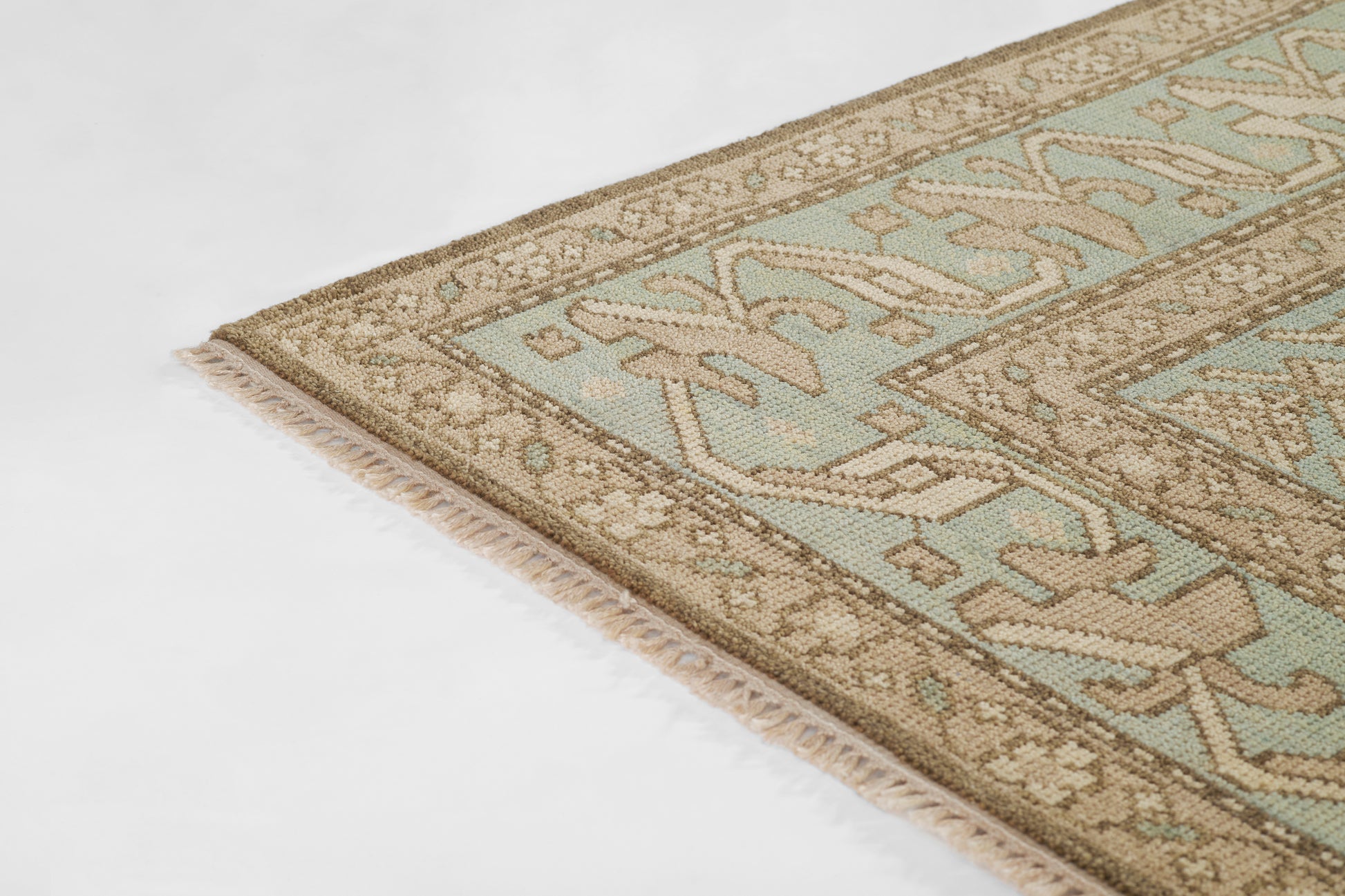 Pastel teal and beige oriental-inspired runner rug with intricate geometric border and cream fringe.