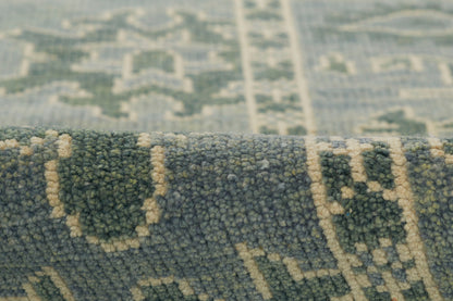 Close-up of a blue-green rug with beige geometric motifs and a soft plush pile.