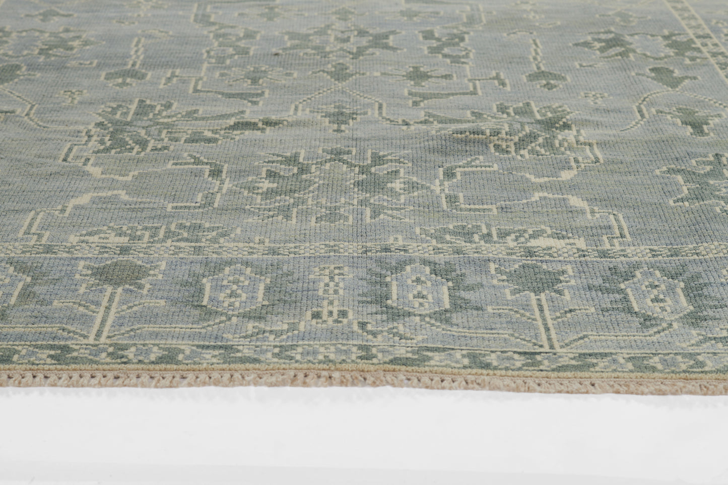 Pale blue nomad-style rug with cream geometric motifs and fringe along edges.