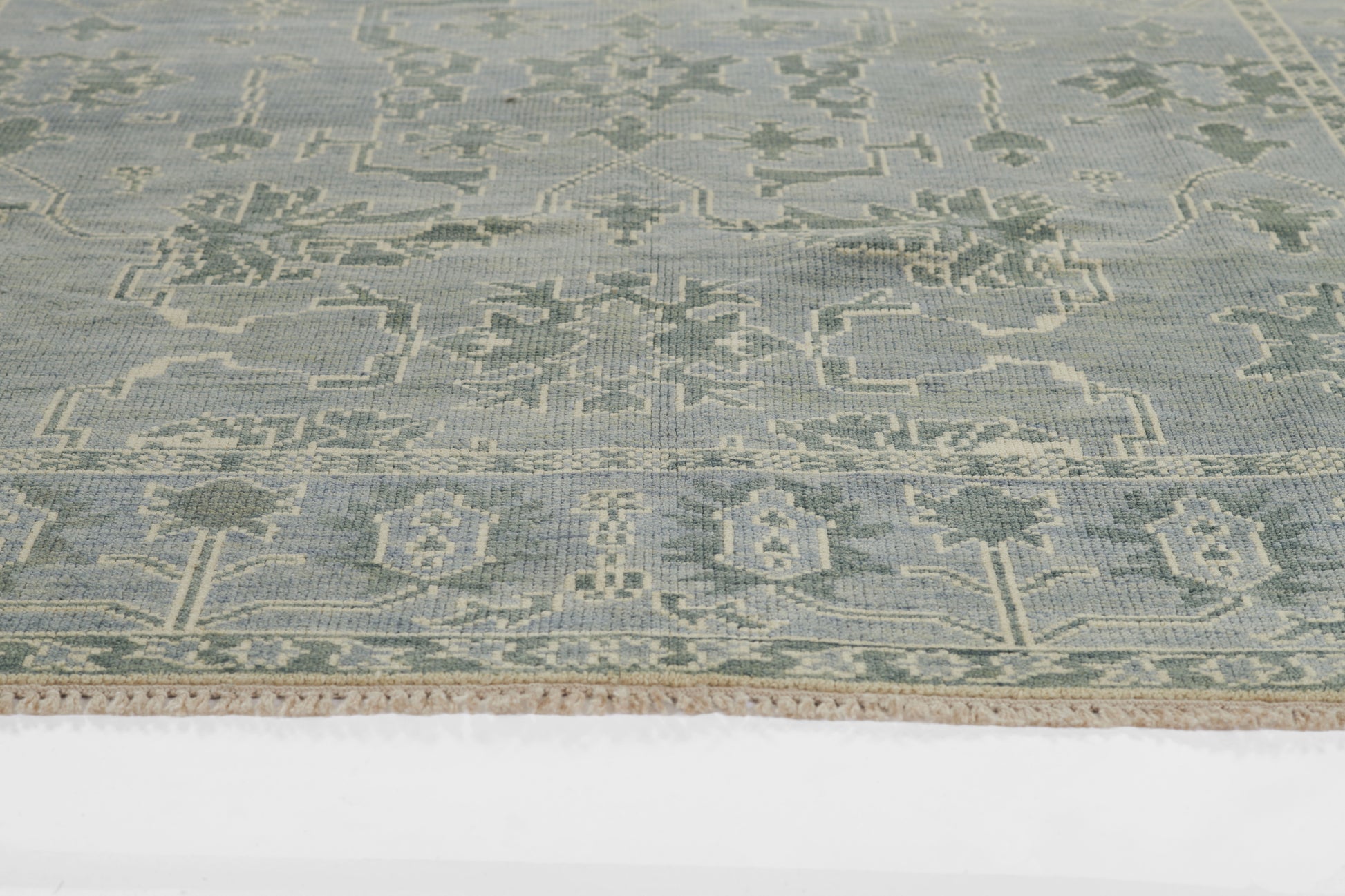 Pale blue nomad-style rug with cream geometric motifs and fringe along edges.