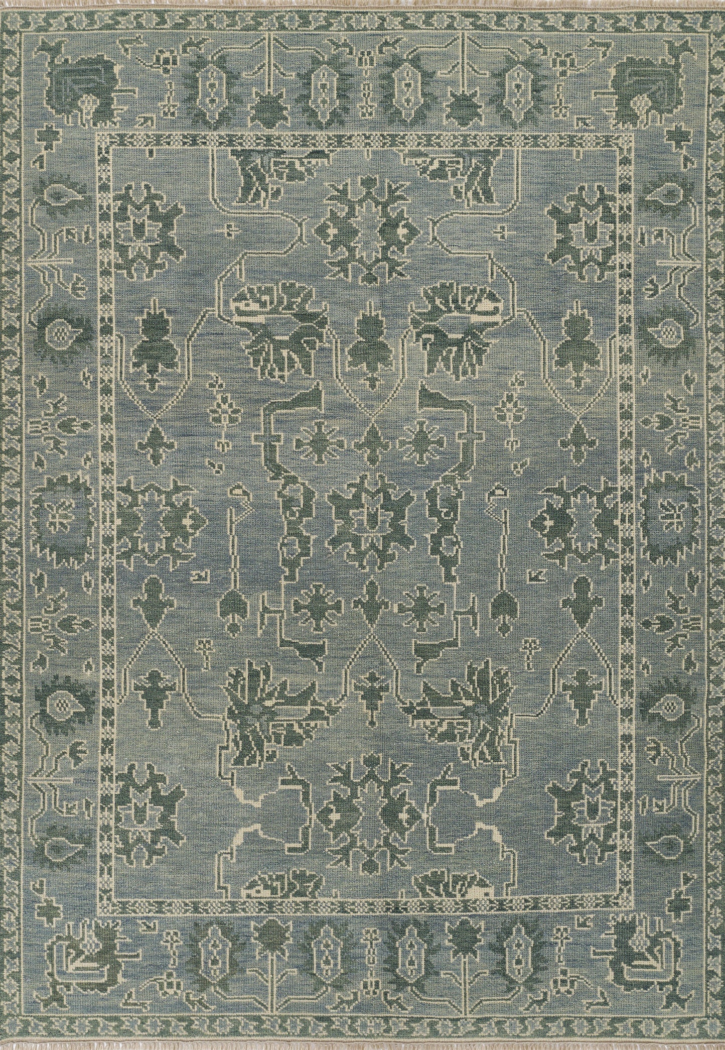 Nomad blue area rug with pale ivory floral medallions and geometric border; distressed antique look, ideal for living room.