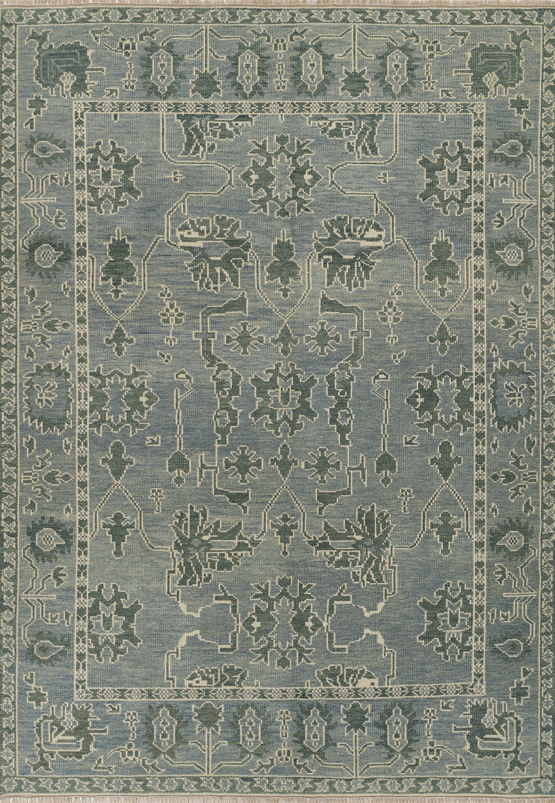 Nomad blue area rug with pale ivory floral medallions and geometric border; distressed antique look, ideal for living room.