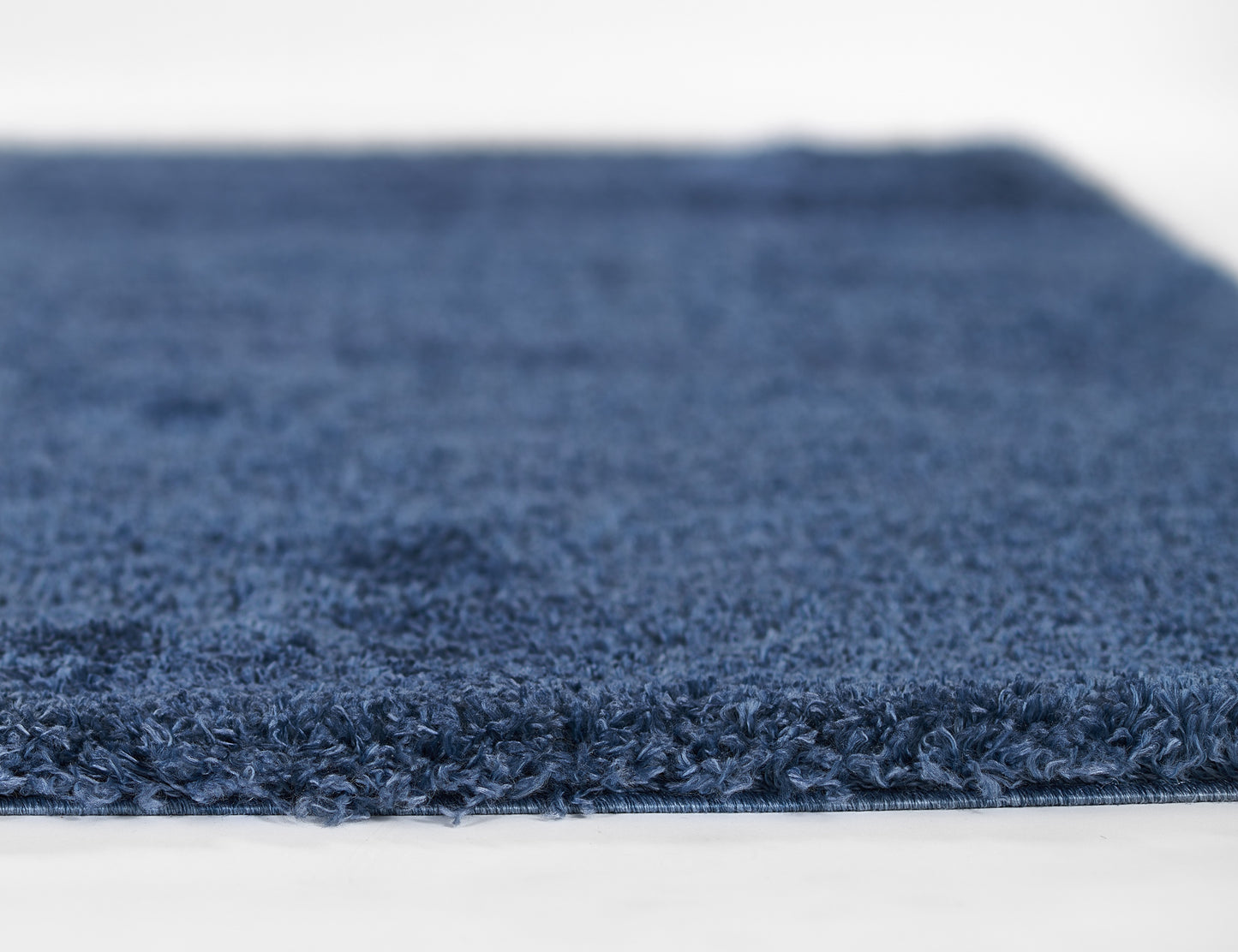 Navy blue shag rug with dense plush pile and finished edge, perfect for living room or bedroom decor.