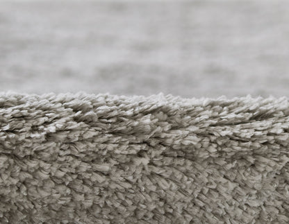 Light gray shag rug close-up, plush faux fur pile with dense fibers for a cozy floor cover