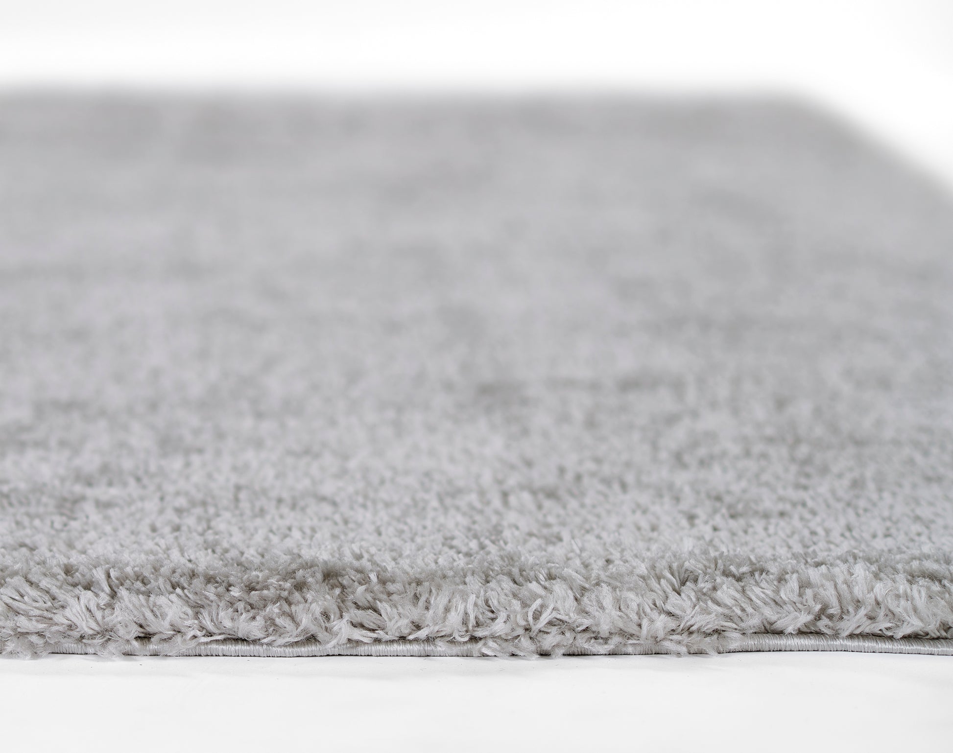 Light gray shag rug with dense fluffy pile and fringed edge.