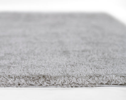 Light gray shag rug with dense fluffy pile and fringed edge.