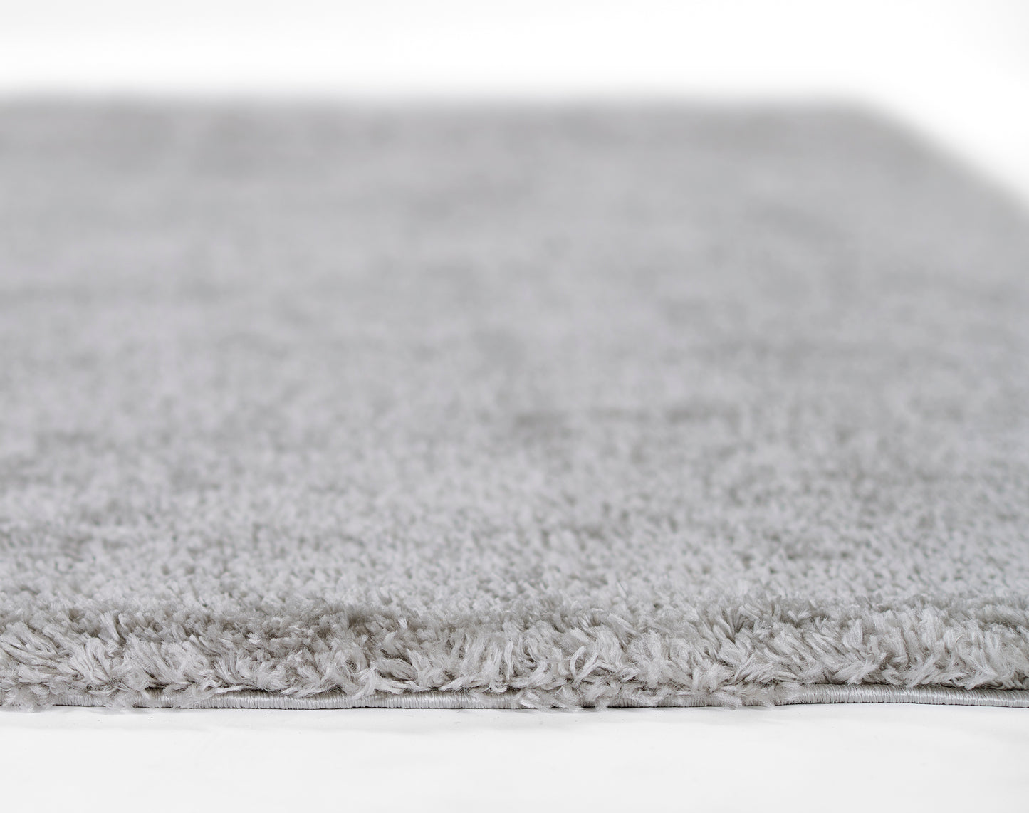 Soft light-gray shag rug with dense plush pile and finished edge, ideal for cozy living spaces.