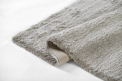 Grey shag rug with thick plush pile and beige non-slip backing; rectangular area rug.