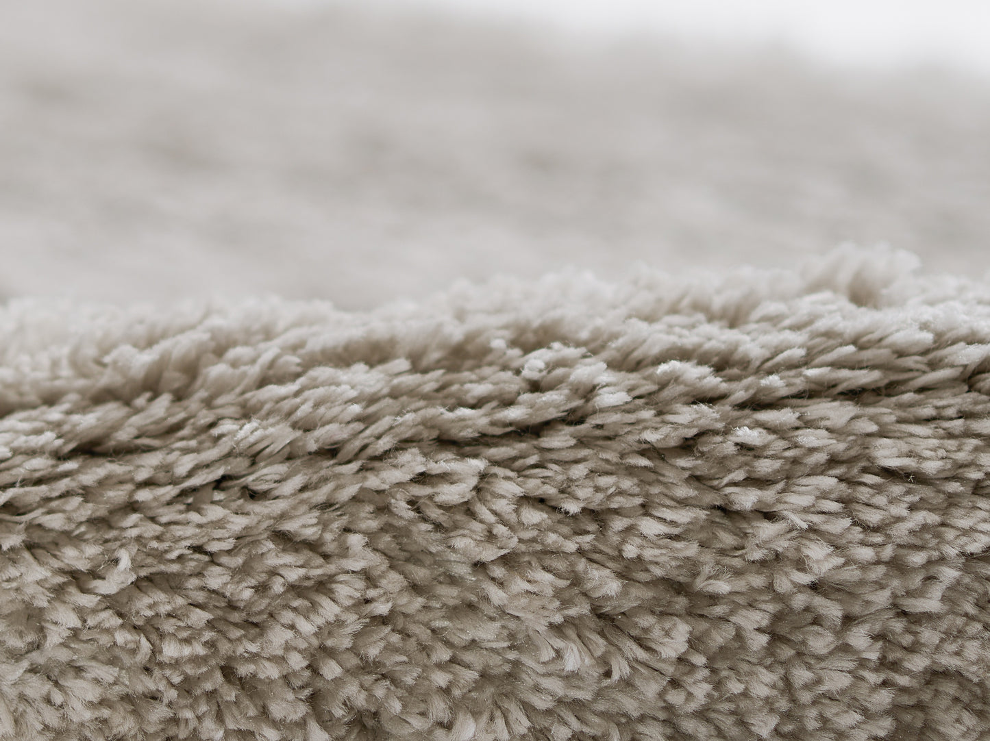 Beige shag rug close-up with dense, plush fibers for a cozy living room look.