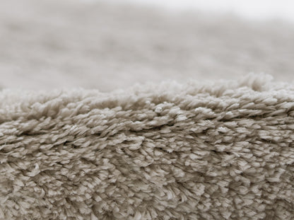 Beige shag rug close-up with dense, plush fibers for a cozy living room look.