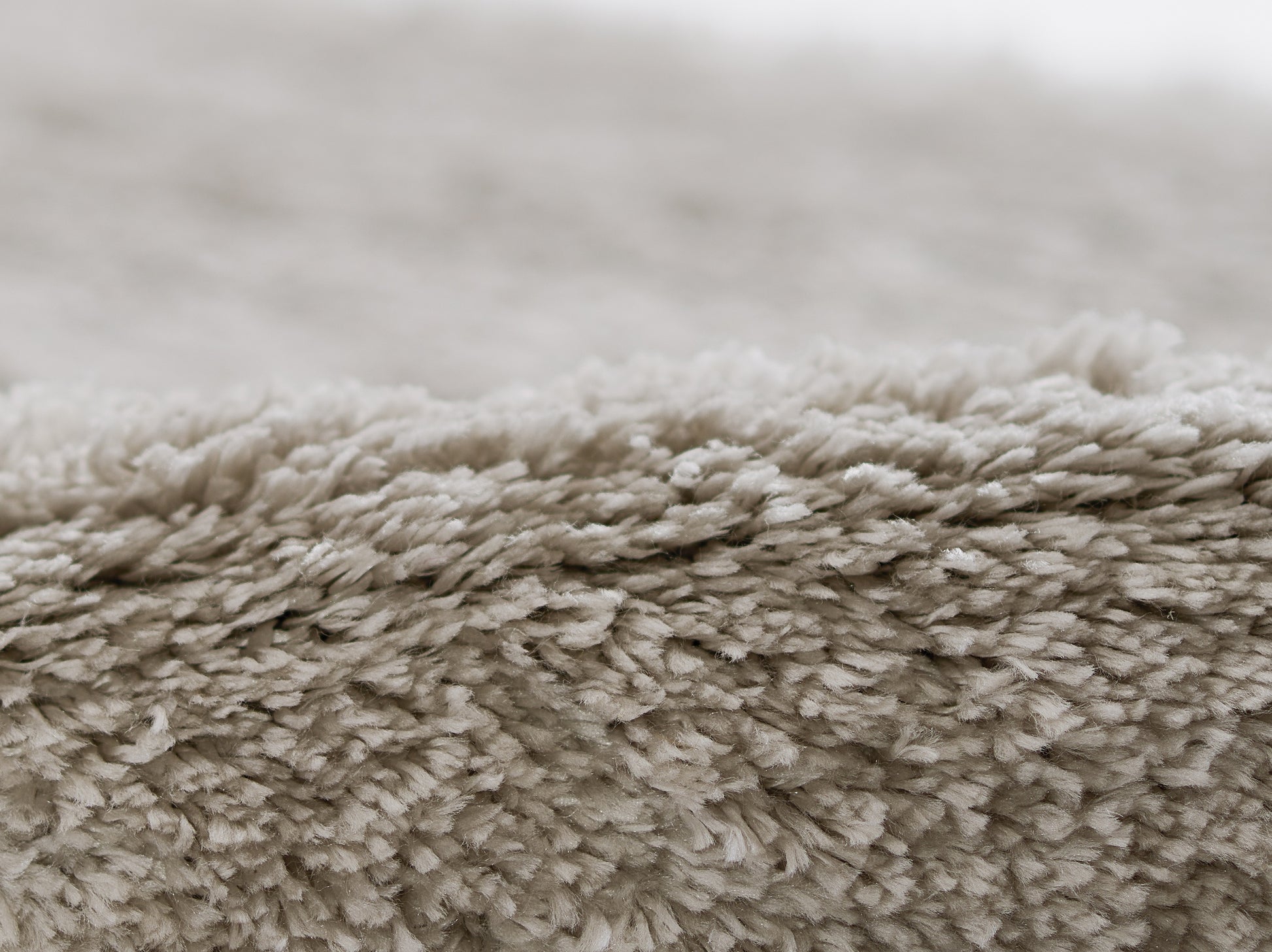Close-up of a beige shag rug with dense plush fibers and soft texture, perfect for cozy living spaces.
