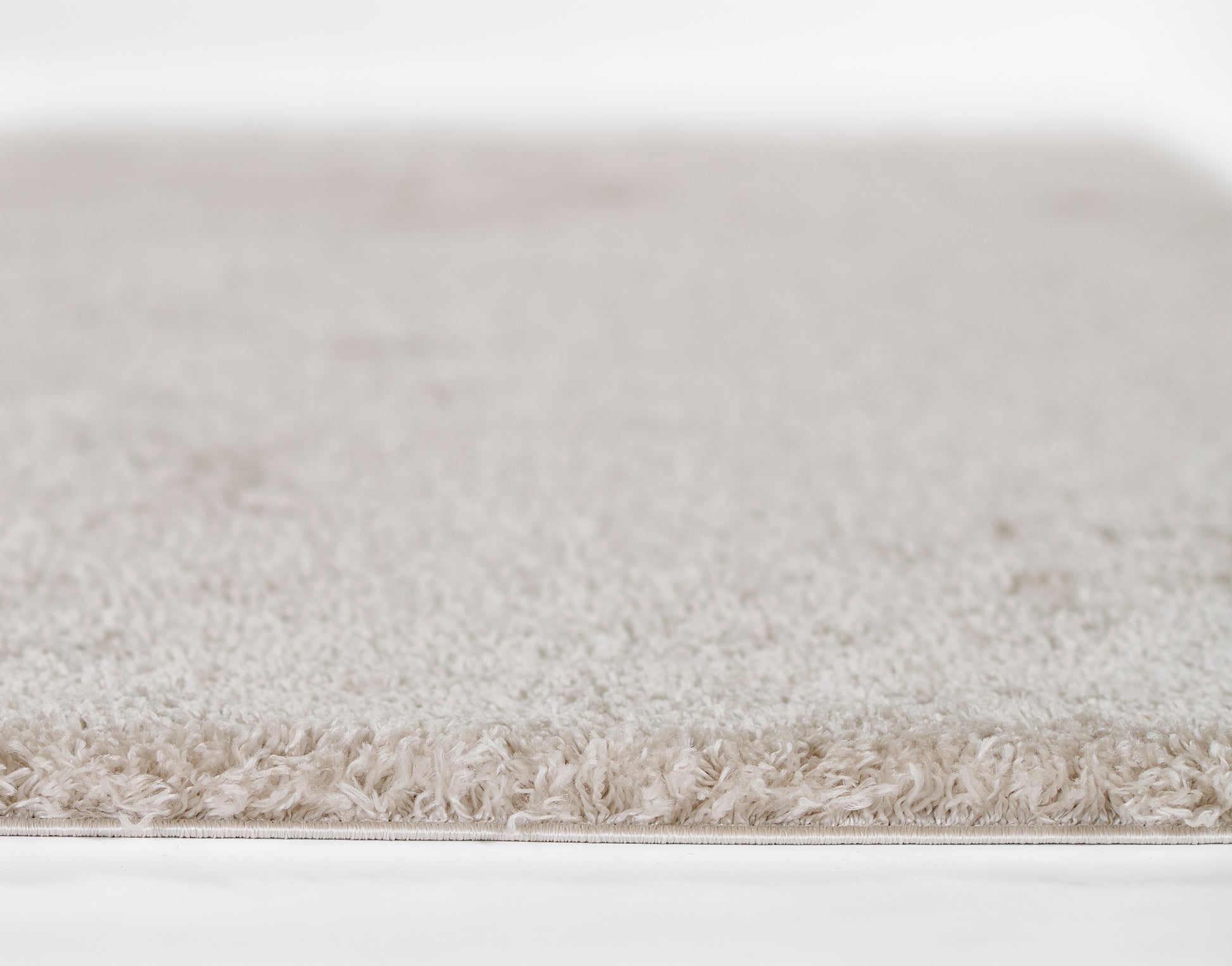Cream beige shag rug with long plush pile and soft fringe edge, neutral living room rug.